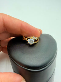 14k This is a yellow gold diamond engagement ring with a twisted band and an accent of smaller stones. With (Cz) stones