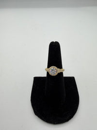 14k This is a yellow gold halo engagement ring with a round center (Cz) stone and pave diamond band.